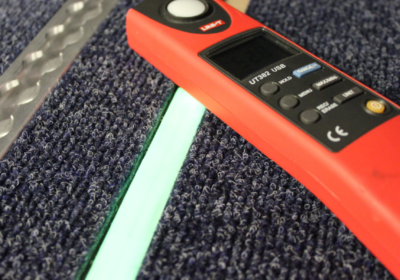 GLS-7 floor path marking system glowing next to a light meter.